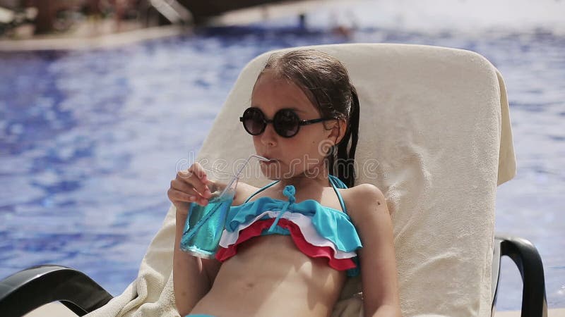 Dziecko dziewczyna w basenie z koktajlem na słońca lounger