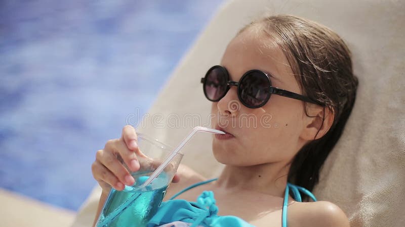 Dziecko dziewczyna w basenie z koktajlem na słońca lounger