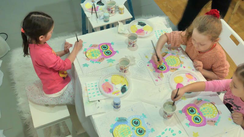 Dziecko dziewczyny i siedzi wpólnie wokoło stołu sala lekcyjnej i rysunku