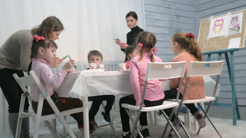Dziecko dziewczyny i siedzi wpólnie wokoło stołu sala lekcyjnej i rysunku Z one są ich potomstwa i