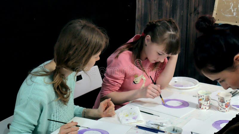 Dziecko dziewczyny i siedzi wpólnie wokoło stołu sala lekcyjnej i rysunku Z one są ich potomstwa i
