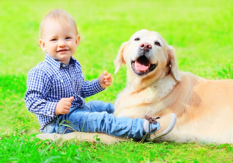 Dziecko i golden retriever pies siedzimy wpólnie na trawie zdjęcie stock