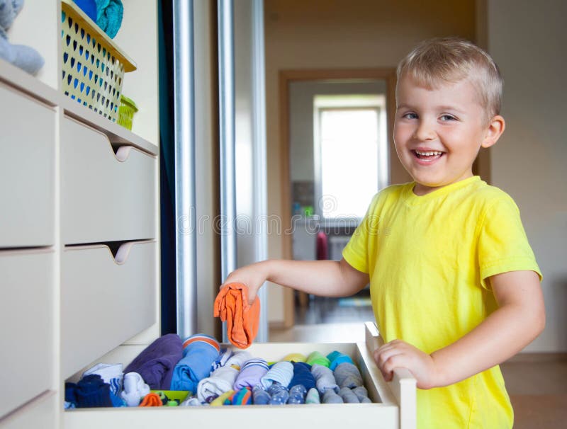 The child puts his clothes on. The boy pulls the T-shirt out. The child puts his clothes on. The boy pulls the T-shirt out