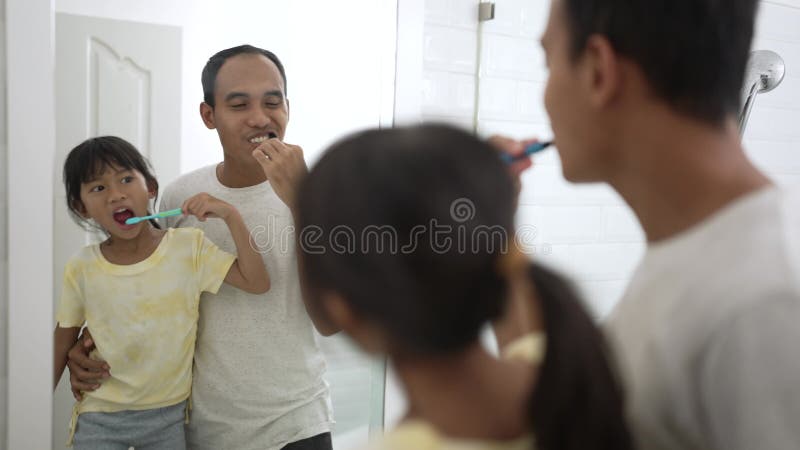 Dziecko uczy się myć zęby z tatą