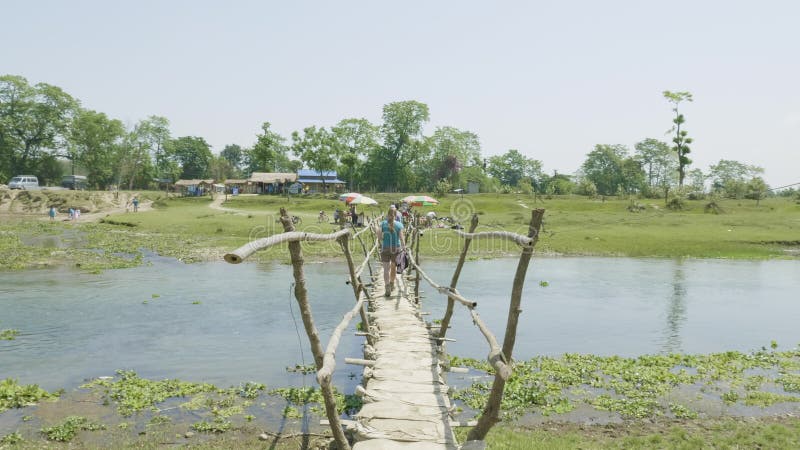 Dziewczyna chodzi wzdłuż drewnianego mosta przez rzeki, Asia, Nepal