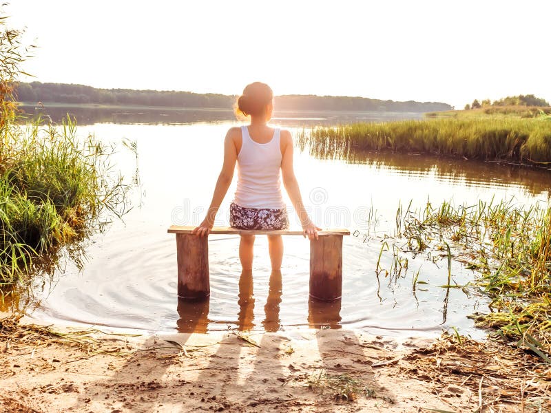 Dziewczyna cieszy się pięknego zmierzchu obsiadanie na ławce rzeką Dziewczyna siedzi blisko wody outdoors Z?oty zmierzchu jezioro zdjęcie stock Dziewczyna cieszy się pięknego zmierzchu obsiadanie na ławce rzeką Dziewczyna siedzi blisko wody outdoors Z?oty zmierzchu jezioro zdjęcie stock