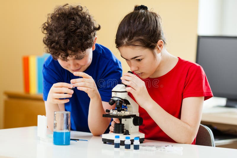 Dziewczyna i chłopiec badający przygotowanie pod mikroskopem