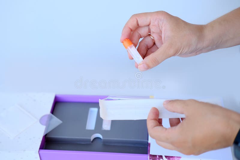 Dziewczyna ma zestaw do testu dna w pudełku z wacikiem do zdrapania nabłonka, zbierając próbkę genetyczną do analizy