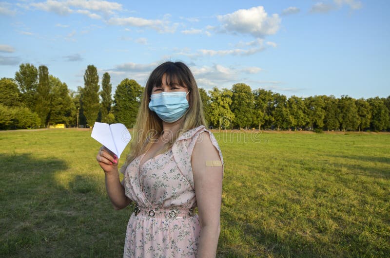 Dziewczyna nosząca maskę ochronną trzymająca się za ręce papierowej płaszczyzny i pokazująca gips w ręku po wstrzyknięciu szczepio obrazy stock