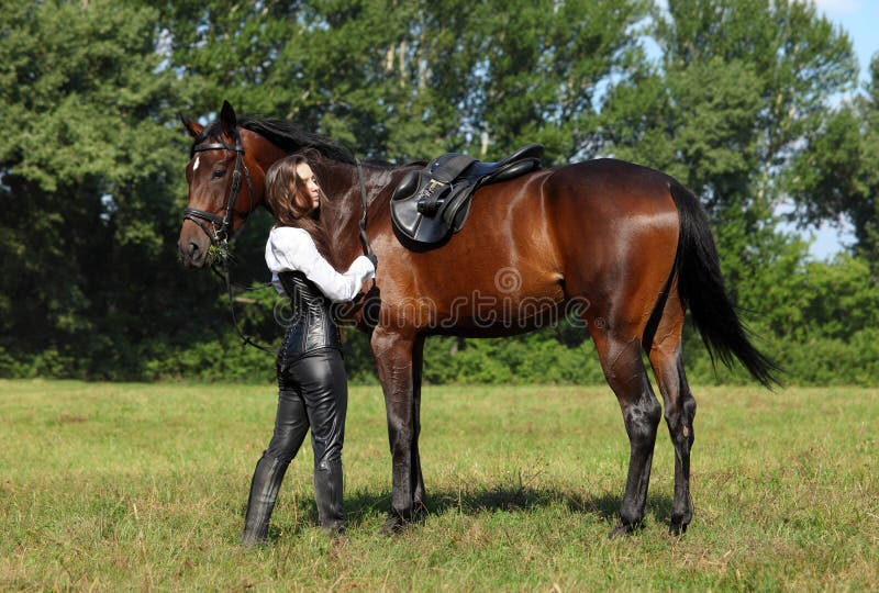 Medieval dressed girl is saddling a horse, english style. Medieval dressed girl is saddling a horse, english style