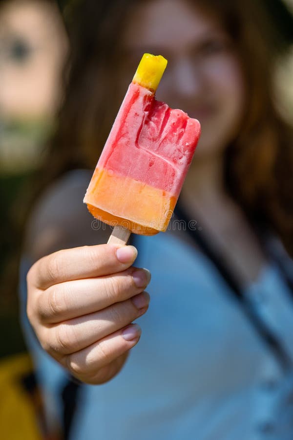 Dziewczyna trzymająca i pokazująca gorzkie czerwone lody jej rozmazana twarz i sylwetka są na tle. kolorowe mrożone owoce zdjęcie royalty free