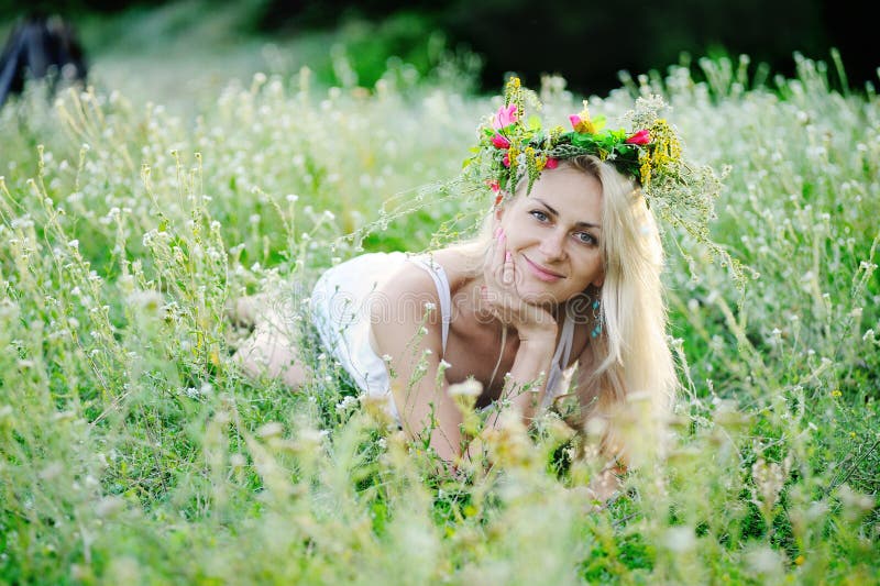 Dziewczyna w biali sundress i wianek kwiaty na jej głowie siedzi