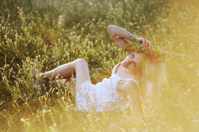 Dziewczyna w biali sundress i wianek kwiaty na jej głowie siedzi