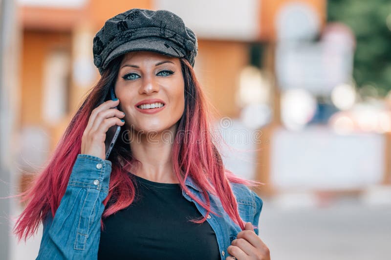 Dziewczyna z czapką i czerwonymi włosami rozmawiająca przez telefon komórkowy fotografia royalty free