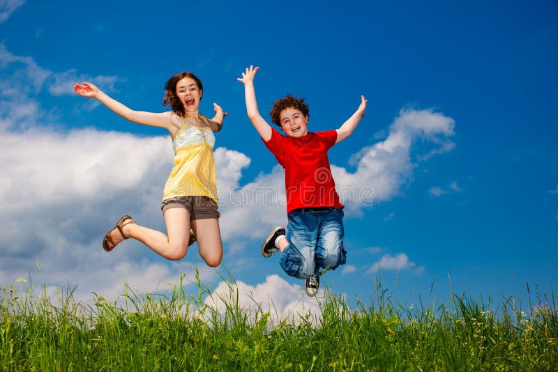 Dziewczynka i chłopiec biegający skoczyć na błękitne niebo