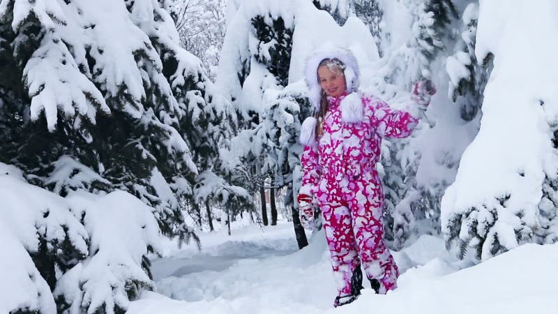 Dziewczynka zimą bawiąca się na śniegu w parku na wolnym powietrzu.