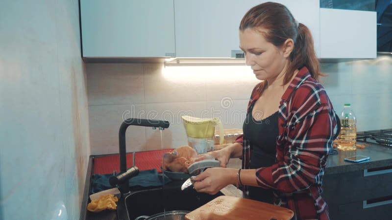 Dziewczyny domycia naczynia w kuchennej tnącej desce Kobieta kucharzi w kuchni dziewczyna myje nóż dalej w zlew obraz stock Dziewczyny domycia naczynia w kuchennej tnącej desce Kobieta kucharzi w kuchni dziewczyna myje nóż dalej w zlew obraz stock