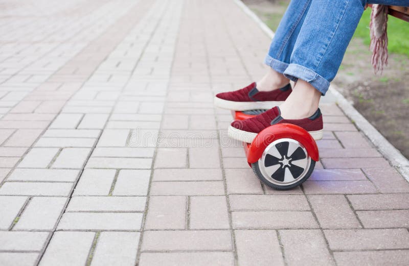 Dziewczyny jazda na nowożytny czerwony elektryczny mini segway lub unosi się deskową hulajnoga obraz royalty free Dziewczyny jazda na nowożytny czerwony elektryczny mini segway lub unosi się deskową hulajnoga obraz royalty free