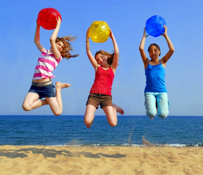 Three girls with colorful beach balls jumping on a seashore. Three girls with colorful beach balls jumping on a seashore