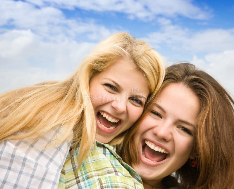 Two happy girls together against cloudy sky. Two happy girls together against cloudy sky