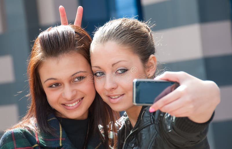 Two happy girls make self-portrait on a street. Two happy girls make self-portrait on a street