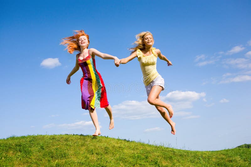 Two happy girls fleeing on a meadow. Against the backdrop of blue sky. Two happy girls fleeing on a meadow. Against the backdrop of blue sky.