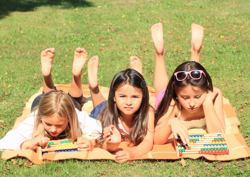 Three lying little barefoot girl playing with two colorful abacuses. Three lying little barefoot girl playing with two colorful abacuses