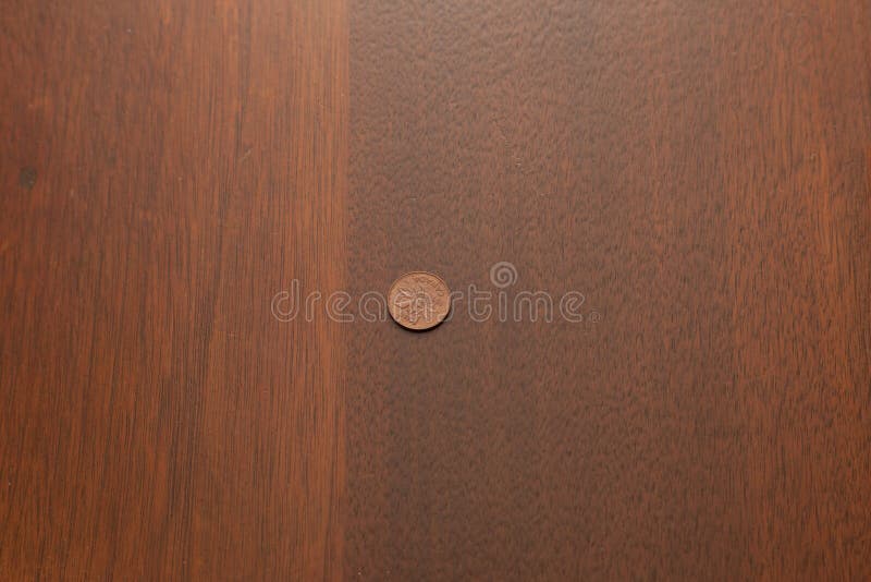 One lonely copper penny sits on a wooden table surrounded by empty copy space. One lonely copper penny sits on a wooden table surrounded by empty copy space