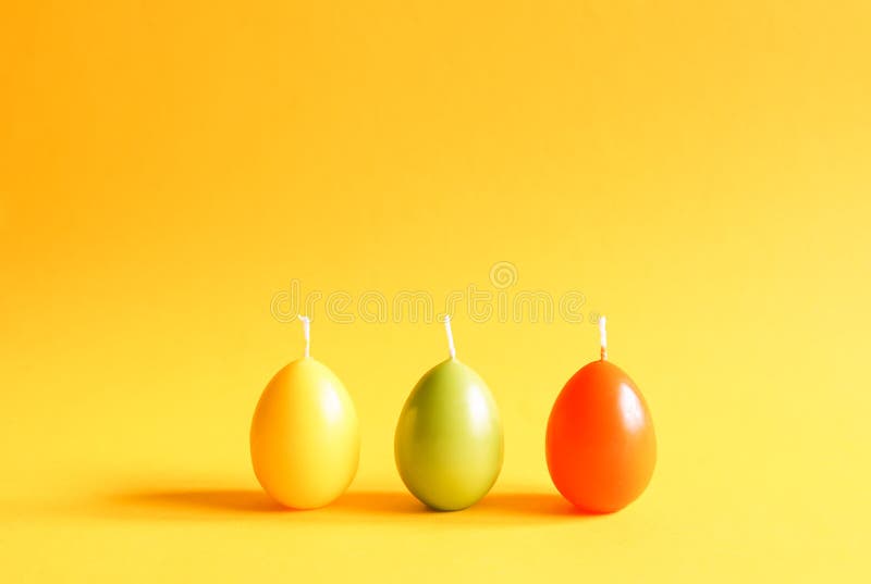 Décor traditionnel de Pâques Groupe de bougies lumineuses de paraffine sous forme d'oeufs colorés sur le fond jaune photos libres de droits Décor traditionnel de Pâques Groupe de bougies lumineuses de paraffine sous forme d'oeufs colorés sur le fond jaune photos libres de droits