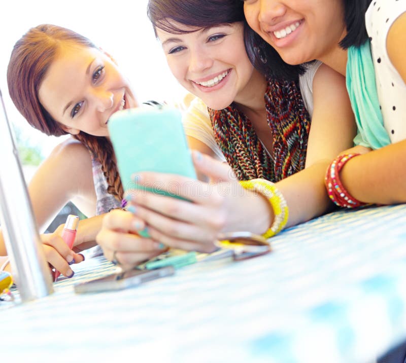 Let me show you this text...A group of adolescent girls laughing as they look at something on a smartphone screen. Let me show you this text...A group of adolescent girls laughing as they look at something on a smartphone screen