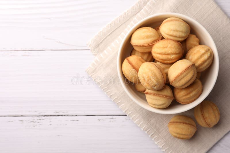Délicieux biscuits en forme de noix avec lait condensé bouilli sur table en bois blanc plat. espace pour le texte