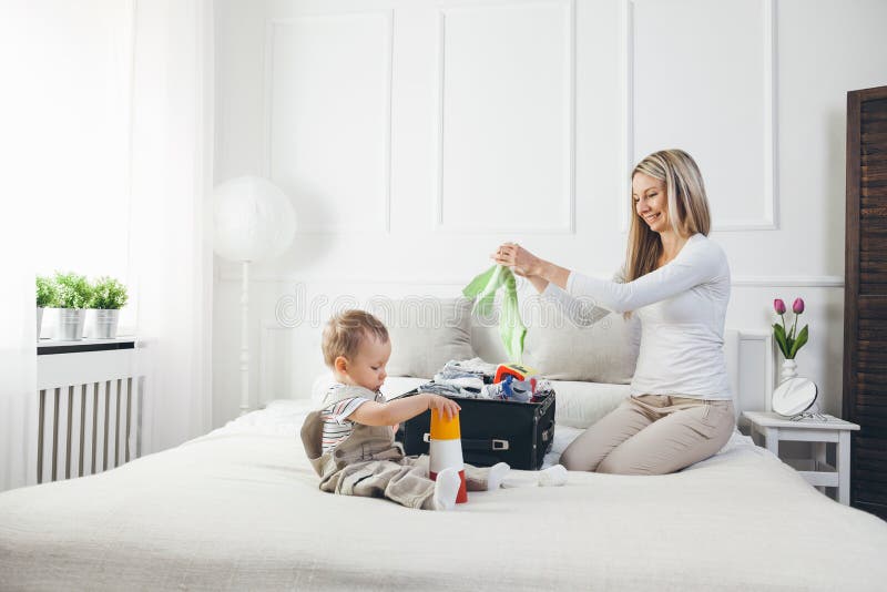 Déplacement avec des enfants La mère heureuse avec son emballage d'enfant vêtx pour des vacances photographie stock