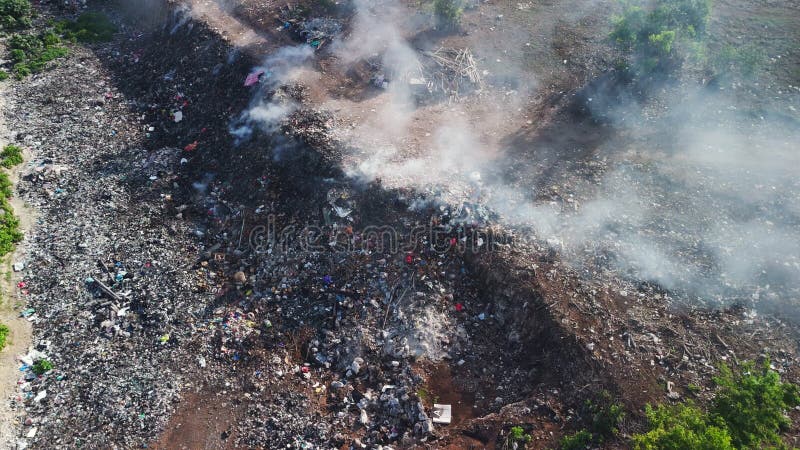Dépotoir illégal avec fumée à Bali. Pollution par les ordures plastiques en brûlant la décharge vue aérienne. banque de vidéos