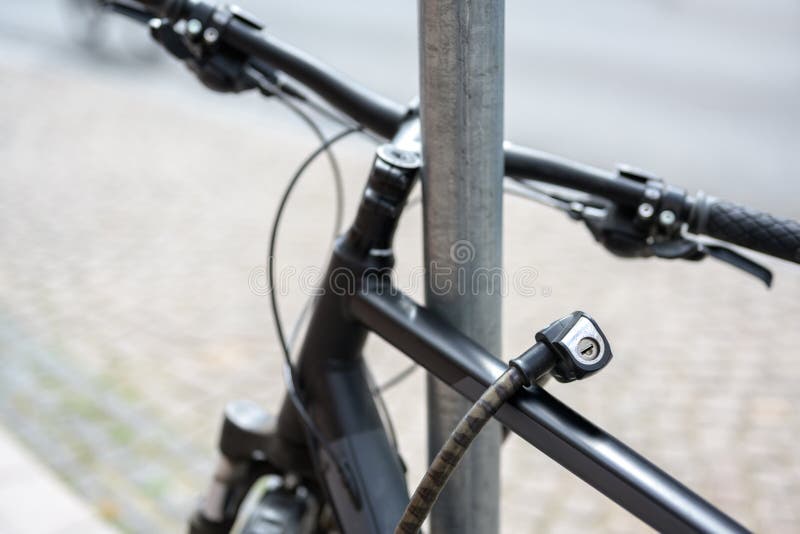 Détail de bicyclette avec serrure attachée à un poteau métallique, concept de protection contre le vol photo stock Détail de bicyclette avec serrure attachée à un poteau métallique, concept de protection contre le vol photo stock
