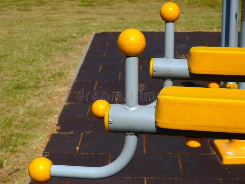 Détail en plastique jaune d'équipement d'exercice en parc poignée en plastique sur le cadre coudé gris de tuyau d'acier photos stock Détail en plastique jaune d'équipement d'exercice en parc poignée en plastique sur le cadre coudé gris de tuyau d'acier photos stock