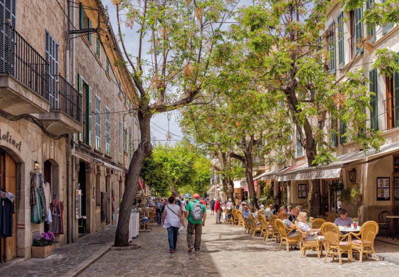 People enjoying drinks, shopping and sightseeing on the Via Blanquerna in the pretty village of Valldemossa. Situated in the hills of the Tramuntana Mountains, Valldemossa is a very popular tourist attraction. People enjoying drinks, shopping and sightseeing on the Via Blanquerna in the pretty village of Valldemossa. Situated in the hills of the Tramuntana Mountains, Valldemossa is a very popular tourist attraction.