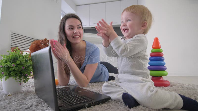 Développement de l'enfant, joyeux garçon infantile curieux avec de jeunes mains d'ordinateur portable et d'applaudissements de bo