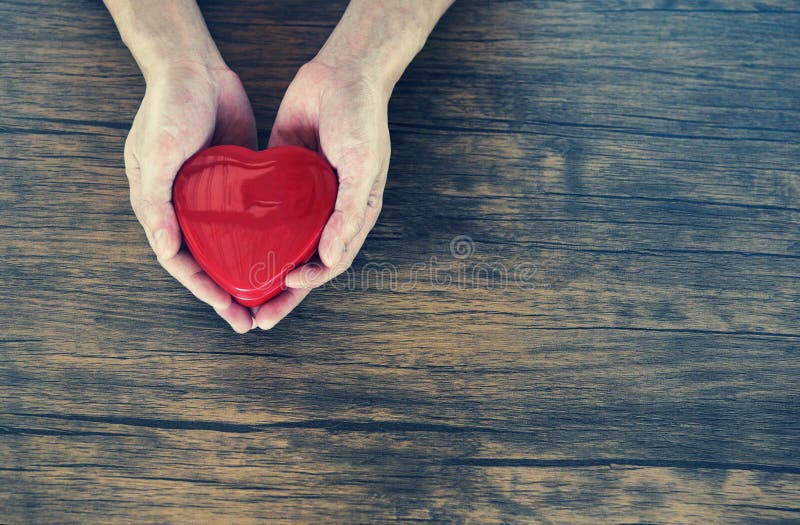 Dê o homem do amor que guarda o coração vermelho nas mãos para o dia de Valentim do amor doam a ajuda dão o calor do amor ciao o
