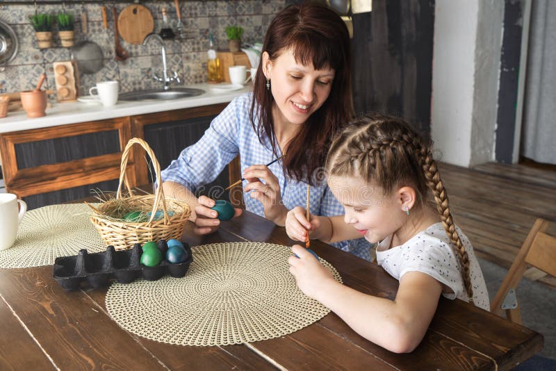 Día de fiesta de Pascua: huevos de la pintura de la madre y de la hija en la cocina y ponerlos en una cesta imagen de archivo Día de fiesta de Pascua: huevos de la pintura de la madre y de la hija en la cocina y ponerlos en una cesta imagen de archivo