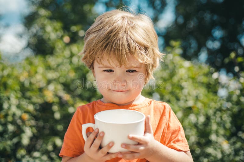 Días de fiesta de los niños en fondo de la naturaleza Leche de la bebida con la taza blanca Ni?o lindo imagen de archivo Días de fiesta de los niños en fondo de la naturaleza Leche de la bebida con la taza blanca Ni?o lindo imagen de archivo