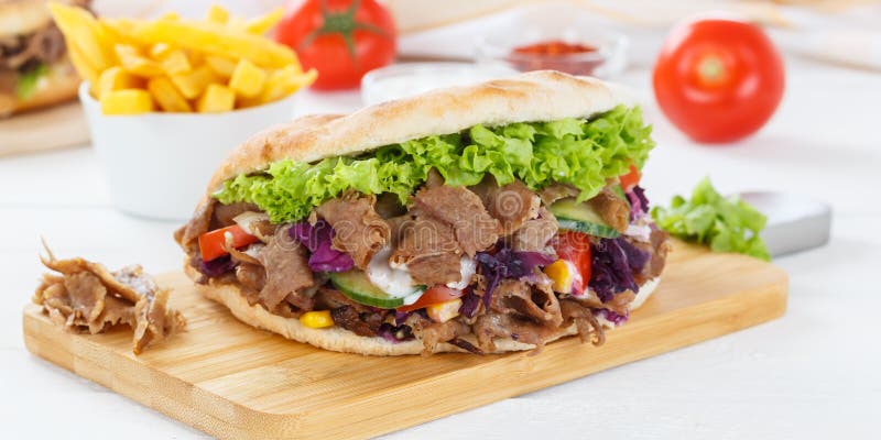 DÃ¶ner Kebab Doner Kebap fast food meal in flatbread with fries on a kitchen board panorama