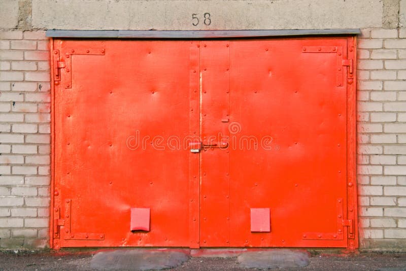 A close up view of a red, metal garage door with the number 58 overhead. A close up view of a red, metal garage door with the number 58 overhead.