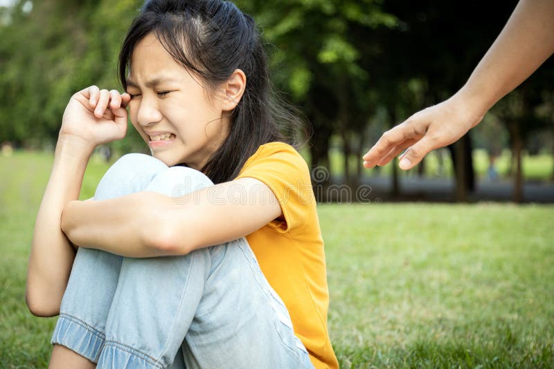 The hand of wishful woman is reaching out to care,help a lost girl,sad asian people sit and crying,get lost or stray from her parents in a city park, missing their parents,grieving, despair, sorrow. The hand of wishful woman is reaching out to care,help a lost girl,sad asian people sit and crying,get lost or stray from her parents in a city park, missing their parents,grieving, despair, sorrow