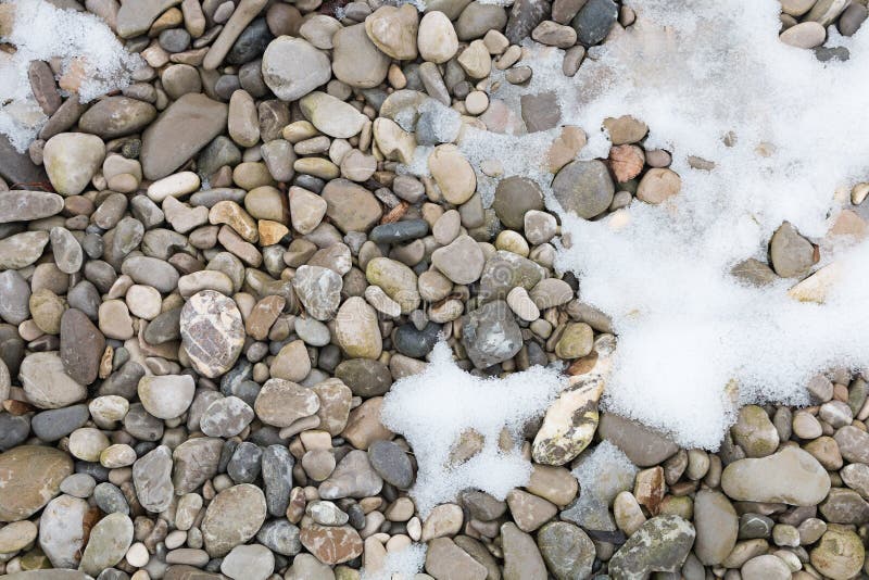 pebble-stones-at-the-riverbank-with-bit-of-snow-foto-de-stock-imagem