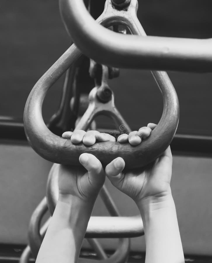 Child`s hands gripping playground equipment. Closeup shot of a child grabbing playground metal bars in black and white.