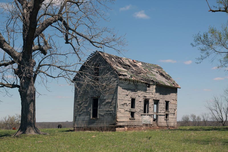 Old outbuilding falling apart in field with a tree and a few small clouds. Old outbuilding falling apart in field with a tree and a few small clouds