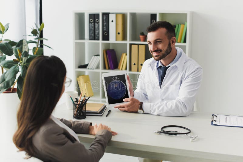 smiling general practitioner showing patient ipad in clinic. smiling general practitioner showing patient ipad in clinic