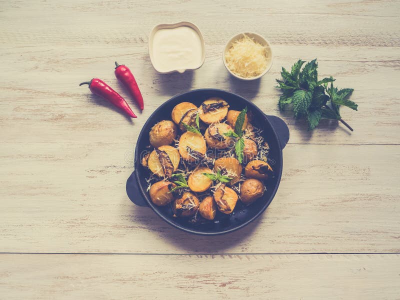 Appetizing pieces of fried potatoes with mushrooms in a frying pan.