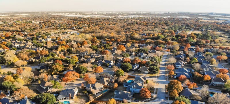 Panorama aerial view residential neighborhood with sprawl subdivision in background. Flyover single-family houses with colorful autumn leaves in Flower Mound, Texas, USA, blue sky. Panorama aerial view residential neighborhood with sprawl subdivision in background. Flyover single-family houses with colorful autumn leaves in Flower Mound, Texas, USA, blue sky