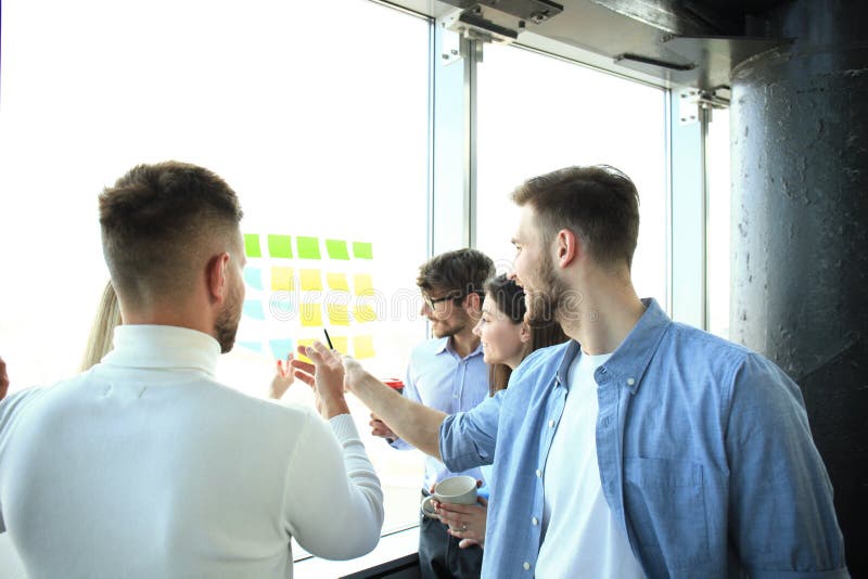Jonge, creatieve startup-ondernemers tijdens een vergadering in een modern kantoor, die plannen en projecten maken met post-it bri stock foto's